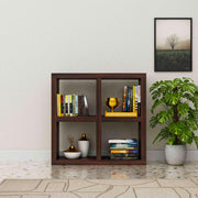 Wooden bookshelf with books and decor items against a light wall with a plant.
