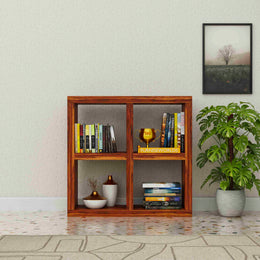 Wooden bookshelf with books and decor items against a light wall with a plant and framed picture.