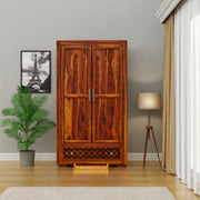 Wooden wardrobe in a room with a lamp and plant, branded 'Furniseworlds'.