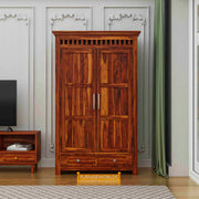 Wooden wardrobe with two doors and two drawers in a room setting with a television and table.