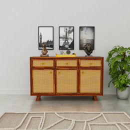 Wooden sideboard with wicker doors in a room with decor elements.