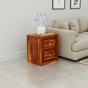 Wooden side table with a lamp next to a beige sofa in a living room.
