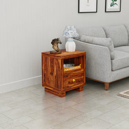 Wooden side table with decorative items next to a gray sofa in a living room.
