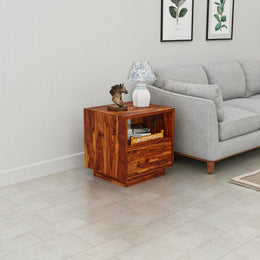 Wooden side table with decorative items next to a gray sofa in a living room.