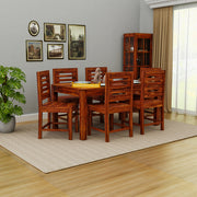Wooden dining set with table and chairs in a room with gray walls and a plant.