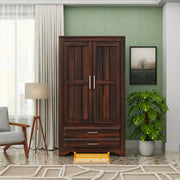 Wooden wardrobe in a room with a lamp, chair, and plant.