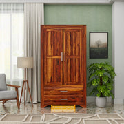 Wooden wardrobe in a room with a lamp, chair, and plant.