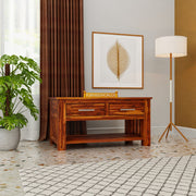 Wooden console table in a room with a plant, lamp, and wall art.