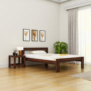 Wooden bed in a room with a side table, lamp, and decor items.