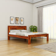 Wooden bed in a room with light-colored walls, a plant, and framed pictures.