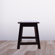 Wooden stool on a wooden floor with a white wall background
