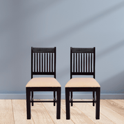 Two black chairs with beige seats against a gray wall.
