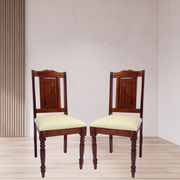Two wooden chairs with cream seats on a light wooden floor and beige wall background
