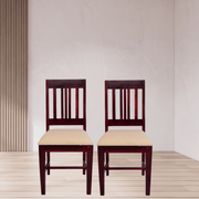 Two wooden chairs with beige seats against a plain wall.