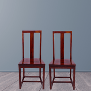 Two wooden chairs against a gray wall.