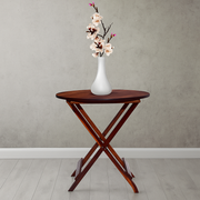 Wooden folding table with a white vase and flowers against a plain wall.