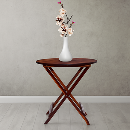 Wooden folding table with a white vase and flowers against a plain wall.