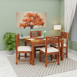 Wooden dining set with four chairs in a room with a painting on the wall.