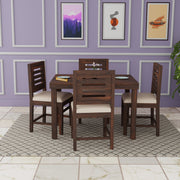 Dining set with wooden table and chairs against a purple wall with framed pictures.